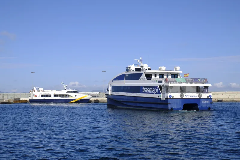 Ferries de las compañías Trasmapi y Mediterránea Pitiusa navegando y atracados en el puerto de La Savina, conectando Formentera con Ibiza. El mar luce azul intenso bajo el sol
